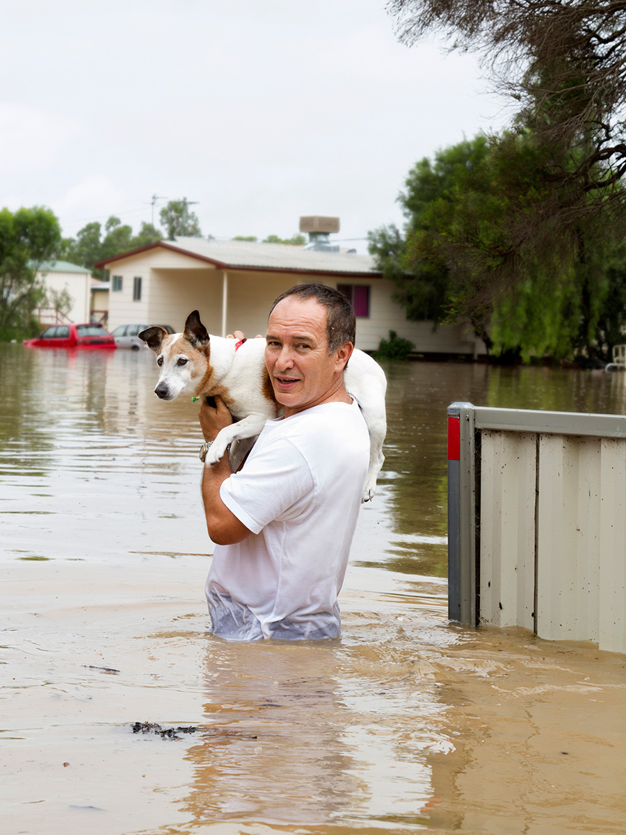 man carrying dog through flood waters